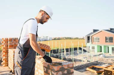 Üniformalı inşaat işçisi ve güvenlik ekipmanı inşaatında çalışıyor.