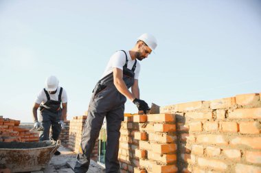 Profesyonel inşaat işçileri bir tuğla ev inşa ediyorlar. Konut inşaatı endüstriyel teması.