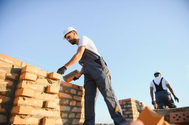 İnşaat alanına tuğla döşeyen bir adam..