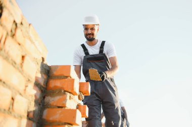 İnşaat alanına tuğla döşeyen bir adam..