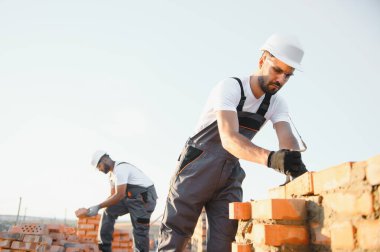 Profesyonel inşaat işçileri bir tuğla ev inşa ediyorlar. Konut inşaatı endüstriyel teması.