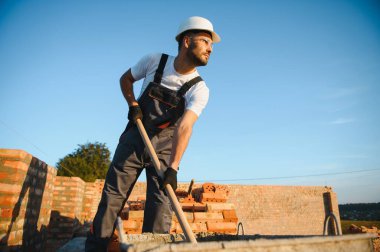 Construction worker in uniform and safety equipment have job on building. Industrial theme.