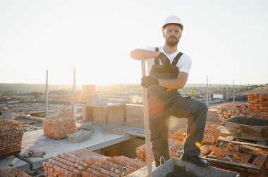 Üniformalı inşaat işçisi ve güvenlik ekipmanı inşaatında çalışıyor.