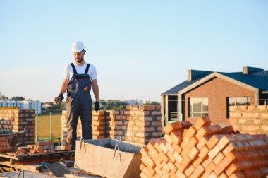 Construction worker man in work clothes and a construction helmet. Portrait of positive male builder in hardhat working at construction site.