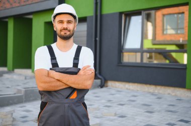 Genç bir profesyonel müteahhit inşa edilmiş kulübelerin yakınında çalışıyor. Uygun fiyatlı aile konutları kavramı.