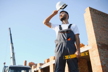 İş yerinde çelik yelek ve şapka takan inşaat işçisinin portresi. İnşaat ve ev tadilatı.