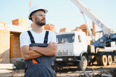 Üniformalı inşaat işçisi ve güvenlik ekipmanı inşaatında çalışıyor.