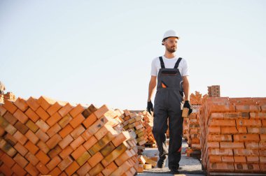 Üniformalı inşaat işçisi ve güvenlik ekipmanı inşaatında çalışıyor.