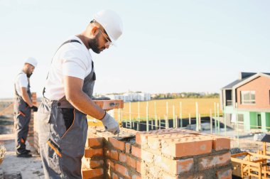 Hintli inşaat işçileri bir tuğla ev inşaatında çalışıyorlar. Bir tuğla duvar inşaatı.
