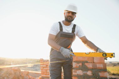 Hintli inşaat işçisi üniforma ve güvenlik ekipmanları inşaatında çalışıyor..