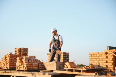 Üniformalı inşaat işçisi ve güvenlik ekipmanı inşaatında çalışıyor.
