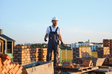 Construction worker man in work clothes and a construction helmet. Portrait of positive male builder in hardhat working at construction site.