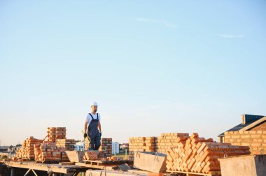 Tuğla duvar kuruluyor. Üniformalı inşaat işçisi ve güvenlik ekipmanı inşaatında çalışıyor.