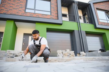 Hintli işçiler kaldırım döşeme döşemeleri, tuğla kaldırım inşaatı, erkek eli eldivenler.