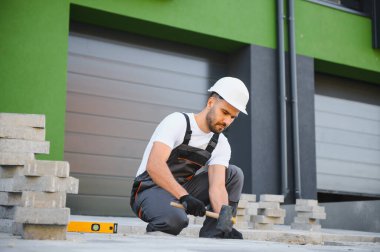İşçi döşeme kiremitleri, tuğla kaldırım inşaatı, eldivenli erkekler.