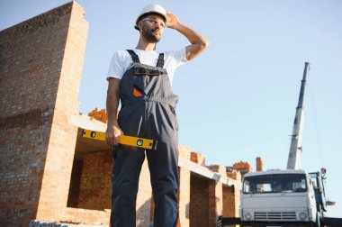 Üniformalı inşaat işçisi ve güvenlik ekipmanı inşaatında çalışıyor.