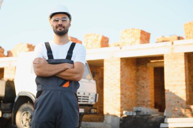 Construction worker in uniform and safety equipment have job on building. Industrial theme.