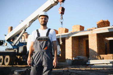 Üniformalı inşaat işçisi ve güvenlik ekipmanı inşaatında çalışıyor.