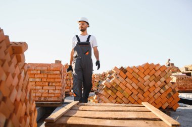 Construction worker man in work clothes and a construction helmet. Portrait of positive male builder in hardhat working at construction site.