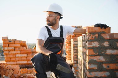 Üniformalı inşaat işçisi ve güvenlik ekipmanı inşaatında çalışıyor.