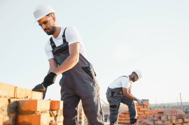 İnşaat alanına tuğla döşeyen bir adam..