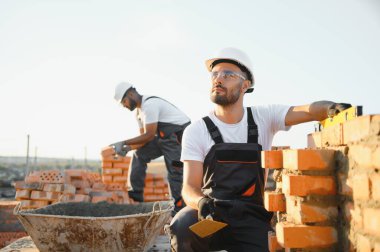 Construction worker in uniform and safety equipment have job on building. Industrial theme.