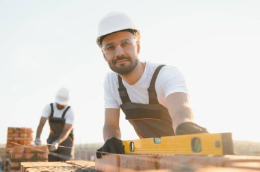 Profesyonel inşaat işçileri bir tuğla ev inşa ediyorlar. Konut inşaatı endüstriyel teması.