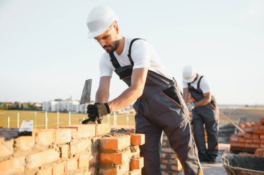Profesyonel inşaat işçileri bir tuğla ev inşa ediyorlar. Konut inşaatı endüstriyel teması.