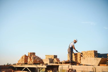 Construction worker in uniform and safety equipment have job on building.