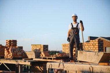 İnşaat alanına tuğla döşeyen bir adam..