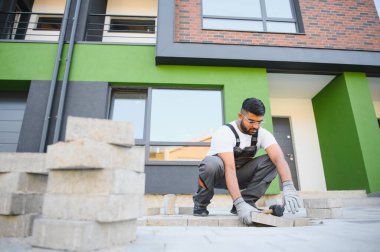 Hintli işçiler kaldırım döşeme döşemeleri, tuğla kaldırım inşaatı, erkek eli eldivenler.