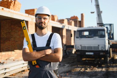 Üniformalı inşaat işçisi ve güvenlik ekipmanı inşaatında çalışıyor.