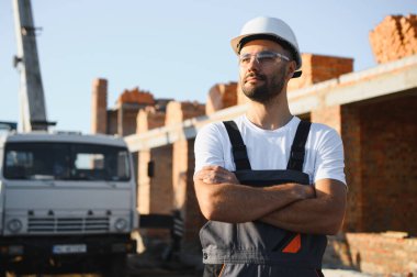 İş yerinde çelik yelek ve şapka takan inşaat işçisinin portresi. İnşaat ve ev tadilatı.