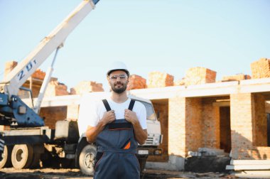 Construction worker in uniform and safety equipment have job on building. Industrial theme.