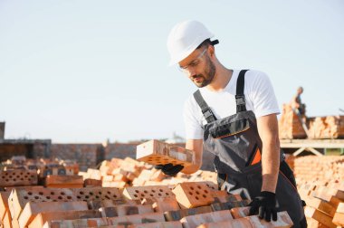 Üniformalı inşaat işçisi ve güvenlik ekipmanı inşaatında çalışıyor.