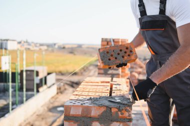 Üniformalı inşaat işçisi ve güvenlik ekipmanı inşaatında çalışıyor.