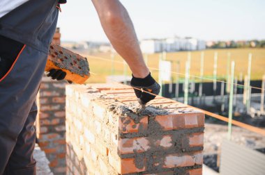 Üniformalı inşaat işçisi ve güvenlik ekipmanı inşaatında çalışıyor.