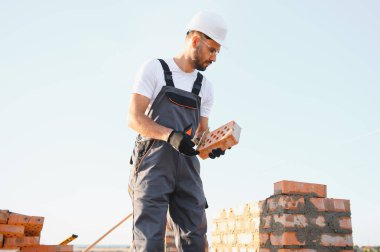 Construction worker in uniform and safety equipment have job on building.