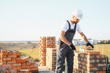 Üniformalı inşaat işçisi ve güvenlik ekipmanı inşaatında çalışıyor.