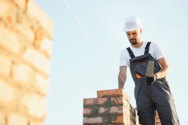 Üniformalı inşaat işçisi ve güvenlik ekipmanı inşaatında çalışıyor.