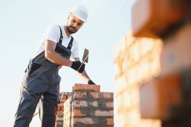 Construction worker in uniform and safety equipment have job on building. Industrial theme.