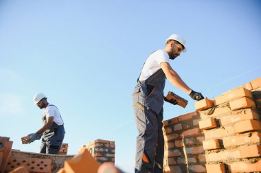 Profesyonel inşaat işçileri bir tuğla ev inşa ediyorlar. Konut inşaatı endüstriyel teması.