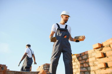 Profesyonel inşaat işçileri bir tuğla ev inşa ediyorlar. Konut inşaatı endüstriyel teması.
