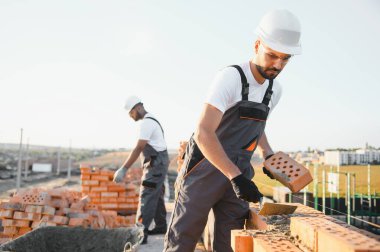 Construction worker in uniform and safety equipment have job on building. Industrial theme.