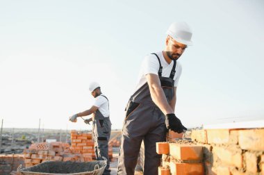 Profesyonel inşaat işçileri bir tuğla ev inşa ediyorlar. Konut inşaatı endüstriyel teması.