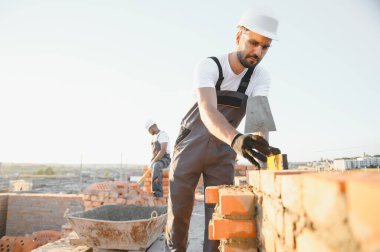 Construction worker in uniform and safety equipment have job on building. Industrial theme.