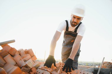Üniformalı inşaat işçisi ve güvenlik ekipmanı inşaatında çalışıyor.