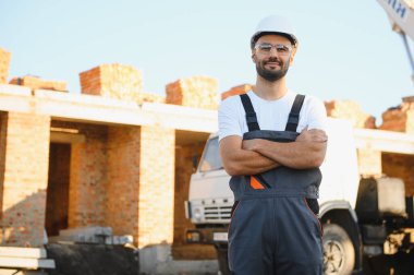 Üniformalı inşaat işçisi ve güvenlik ekipmanı inşaatında çalışıyor.