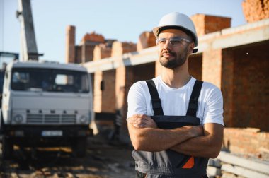 Üniformalı inşaat işçisi ve güvenlik ekipmanı inşaatında çalışıyor.