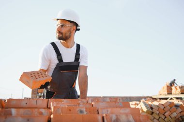 Construction worker in uniform and safety equipment have job on building. Industrial theme.
